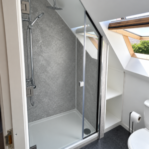 Store Bespoke glass shower door and shaped side panel beneath a sloping ceiling