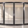 Four-panel curved sliding glass door with dark aluminium frames in a modern showroom